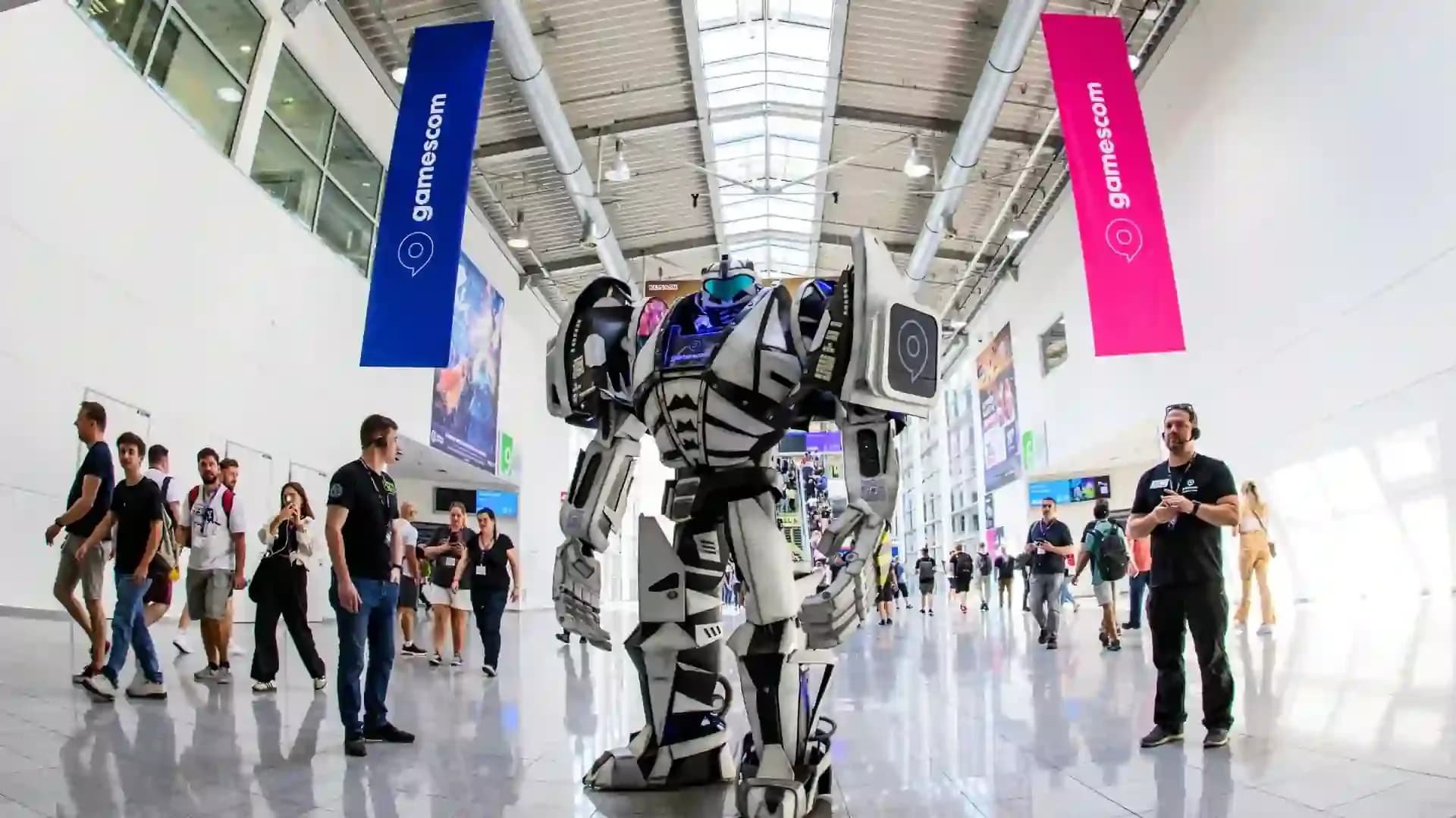 Posjetitelji i veliki robot u izložbenom prostoru Gamescoma