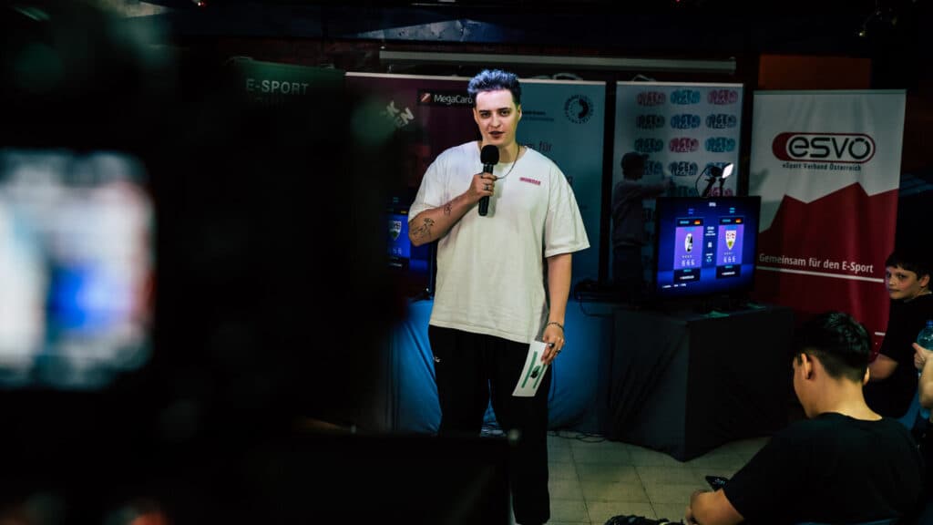 Voditelj na austrijskom esports događaju uz ekran nogometne videoigre