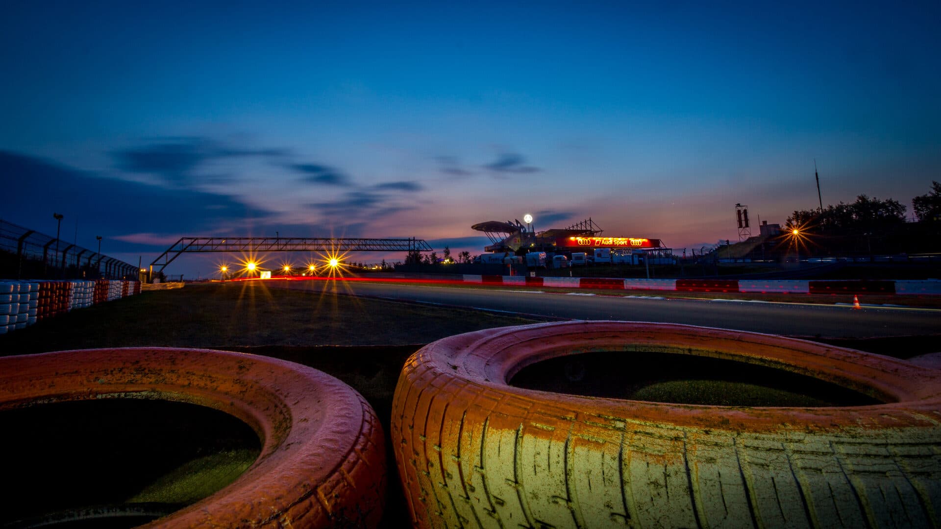 Arhivska fotografija GP dijela staze Nürburgring noću 2014., s barijerama od guma u prvom planu i svjetlosnim tragom na asfaltu.